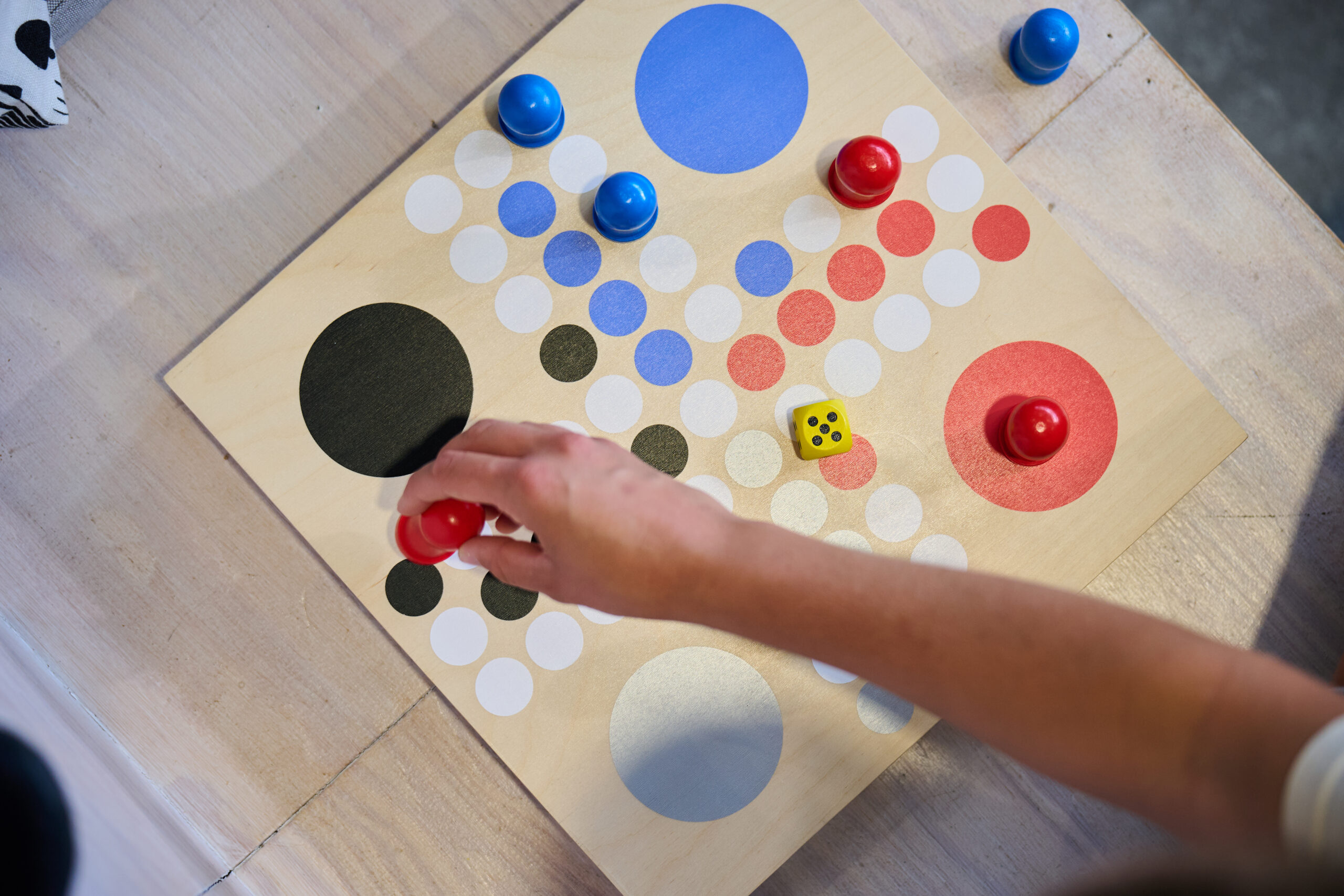 Hand moving a game piece on a wooden board game.