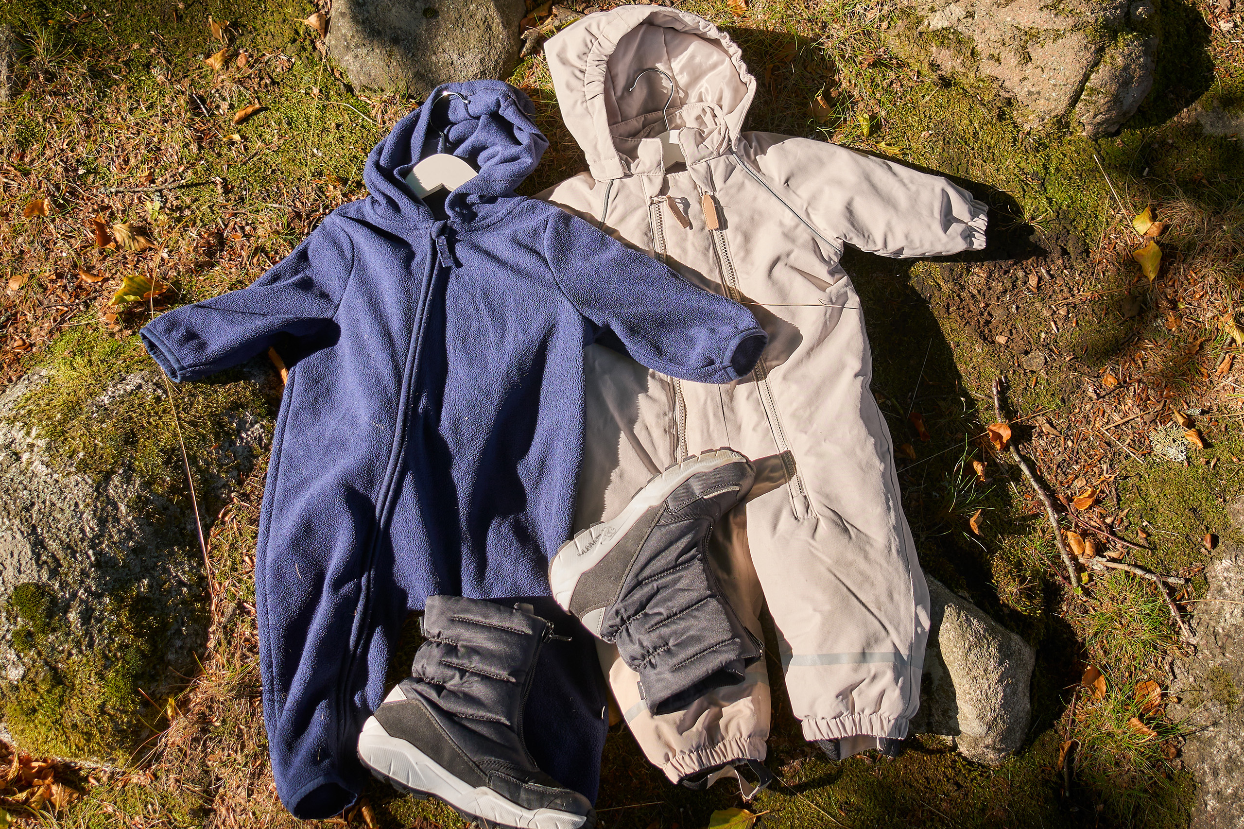 Two kids overalls displayed outside in the forest.